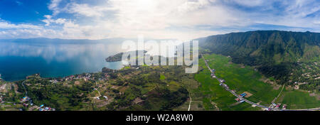 Antenne: Toba-See und die Insel Samosir Blick von oben Sumatra Indonesien. Riesige vulkanische Caldera von Wasser bedeckt, traditionelle Batak Dörfer, grüne Reis Stockfoto