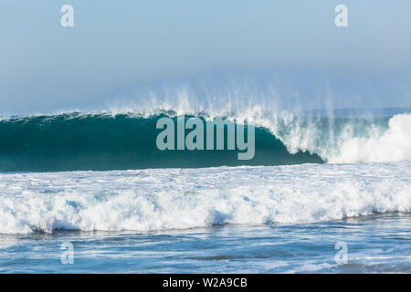 Ocean Wave blau Wand aus Wasser Strom krachen brechen auf flache Reef Beach Küste. Stockfoto