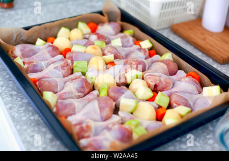 Hähnchenkeulen mit Gemüse bereit, auf Backblech in der Küche zu kochen. Stockfoto