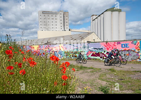 Eine Gruppe von Radfahrern, Graffiti, Klatschmohn und Chancelot Mühle in Leith, Edinburgh, Schottland, Großbritannien. Stockfoto