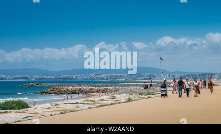 Caparica, Portugal - Juli 5, 2019: Leute an der Strandpromenade im sonnigen Sommertag. Costa da Caparica ist berühmt touristische Destination in der Nähe von Lissabon Stockfoto