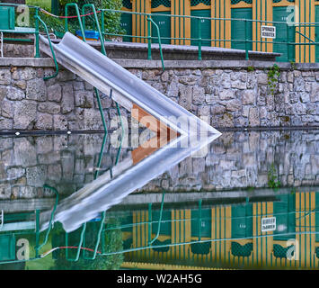 Eine historische Natürliche Thermalbad in Bad Fischau, Österreich. Eine metallische Folie in den Pool und Holzhütten mit ihrer Reflexion im kristallklaren Wasser Stockfoto