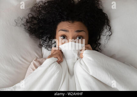 Überrascht, lustig, afrikanische Mädchen im Bett für Gesicht mit Decke Stockfoto