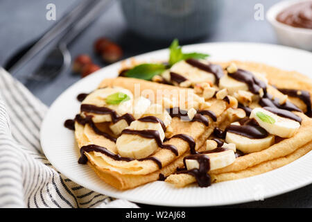 Banane und Schokolade Soße auf gefaltete Crepes, Französisches Frühstück oder Dessert. Detailansicht, selektiver Fokus Stockfoto