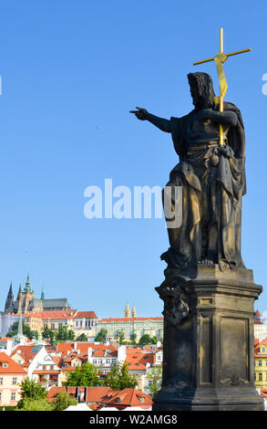 Religiöse statue Zeigefinger auf der berühmten Karlsbrücke in Prag, Böhmen, Tschechien. Die Prager Burg und das historische Zentrum im Hintergrund. Blauer Himmel, vertikale Bild. Erstaunliche Städte, Europa. Stockfoto