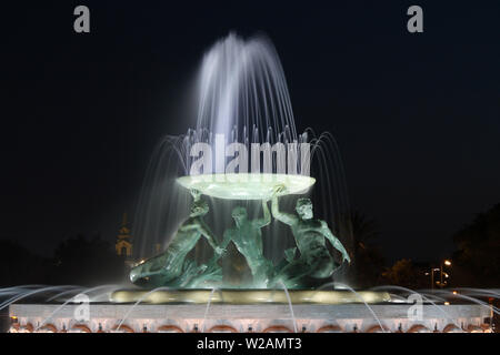 Valletta, Malta - der Tritons-Brunnen am Stadttor, der nachts beleuchtet wird. Nahaufnahme des Denkmals. Stockfoto