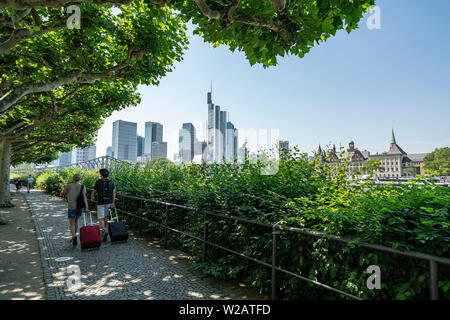 Frankfurt am Main, Deutschland. Juli 2019. einer von Bäumen gesäumten Straße mit der Wolkenkratzer Skyline im Hintergrund Stockfoto