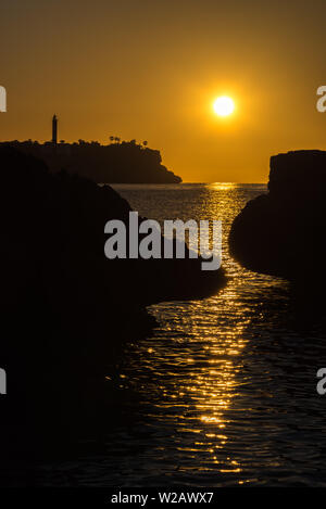 Der Leuchtturm und das Meer vor Porto Colom bei Sonnenaufgang Stockfoto