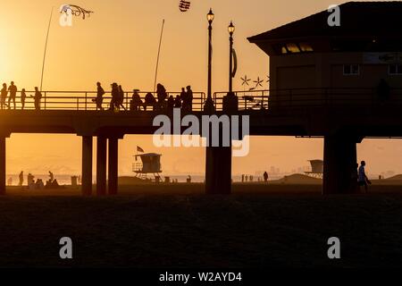 Silhouetten, die an der Huntington Beach Pier bei Sonnenuntergang Stockfoto