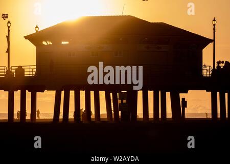 Silhouetten, die an der Huntington Beach Pier bei Sonnenuntergang Stockfoto