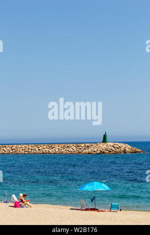 Frau sitzt auf einem Strand in Spanien mit einem Freund Stockfoto