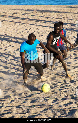 Die afrikanischen Männer am Strand Fußball spielen Stockfoto