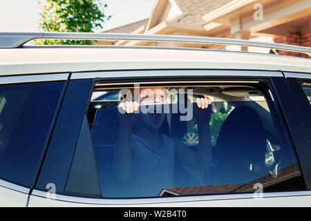 Preschooler wenig Kaukasische Mädchen alleine im Auto während der heißen sonnigen Tag. Kind schreien schreien, die versuchen, aus geschlossenen Fahrzeug im Sommer zu erhalten. Stockfoto