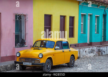 Trinidad, Kuba - Juni 6, 2019: Alte gelbe Auto mit bunten Gebäude im Hintergrund in einer kleinen kubanischen Stadt während einer lebendigen sonnigen Tag. Stockfoto