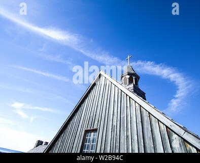 Kirchturm mit Platz kopieren. Land hölzerne Kirchturm gegen einen sonnigen blauen Himmel mit einem hölzernen Kreuz auf der Spitze. Stockfoto