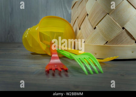 Bunte Plastikgabeln und kippten Weidenkorb auf rustikalen Holzmöbeln Hintergrund in Nahaufnahme. Recycling von Kunststoffen Konzept Bild Stockfoto
