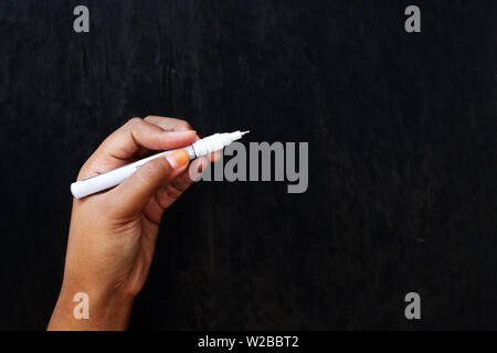 Braune Haut Mädchen, dass weiße Markierung auf schwarzem Holz Vorstand Hintergrund Stockfoto