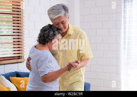 Asiatischer seniors Paar genießen Tanzen im Wohnzimmer zu Hause. Altern zu Hause Konzept Stockfoto