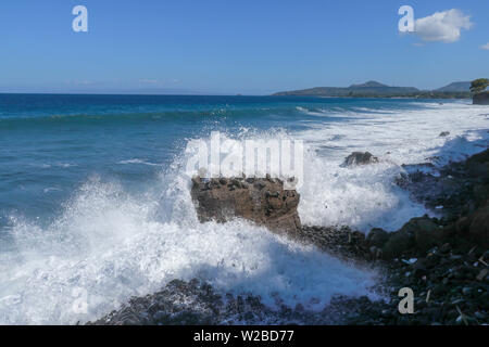 Die Wellen brechen an einem steinigen Strand und bilden einen großen Spray. Großwellen-Crash gegen die Felsen während eines Sturms in den Tropen. Starke Wellen Stockfoto