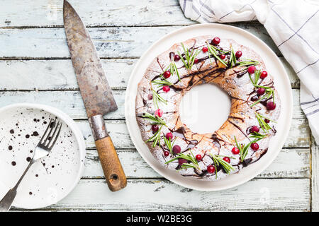 Preiselbeeren bundt Cake mit Schokolade und Orange auf einem weißen Teller. Hausgemachte Herbst und Winter gemütliches Dessert auf rustikalen Holztisch, Ansicht von oben Stockfoto