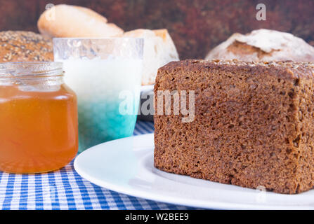 Bunte Foto eines Stückes Mehrkornbrot mit Joghurt und einem marmeladenglas begleitet. Stockfoto