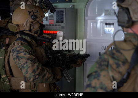 Force Reconnaissance Marines mit maritimen Raid-Kraft, 31 Marine Expeditionary Unit, bereiten Sie eine Tür zu einer Verletzung beim Löschen der Brücke bei einem Besuch, Board, Durchsuchung und Beschlagnahme Übung an Bord der Amphibischen dock Landung Schiff USS Ashland (LSD 48), unterwegs in der Coral Sea, 29. Juni 2019. Ashland, Teil der Wasp amphibischen bereit, Gruppe, mit Eingeschifft 31 MEU, arbeitet in der indopazifischen Region Interoperabilität mit Partnern zu verbessern und dienen als ready-Response Force für jede Art von Kontingenz, und stellen gleichzeitig eine flexible und tödliche Krise Response Force bereit zu Pe Stockfoto