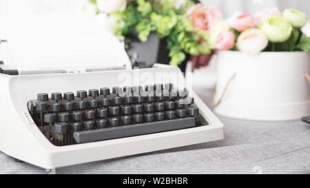 Vintage Schreibmaschine mit Papier. retro Maschine Technologie - weißer Hintergrund mit Blumen Stockfoto