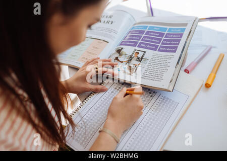 Test Überprüfung. Konzentriert brünette Frauen beugen Kopf beim Notizen zu machen Stockfoto