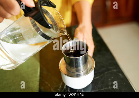 Close-up Bild der Frau Füllung traditionellen vietnamesischen Kaffee drücken Sie mit heißem Wasser Stockfoto