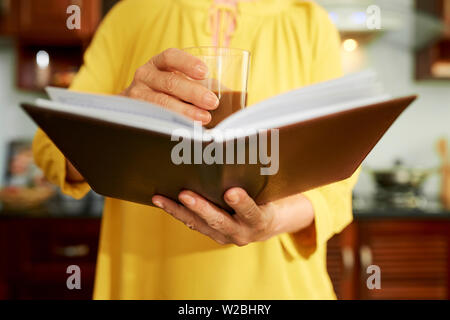 Close-up Bild der Frau Glas mit starkem Kaffee und Lesen gutes Buch am Morgen Stockfoto