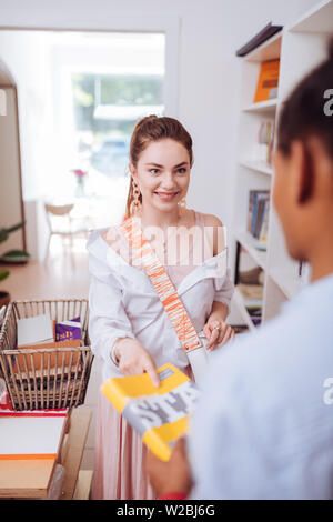 Ziemlich weiblich. Cute brunette halten Lächeln auf ihrem Gesicht, während sie unter Stockfoto