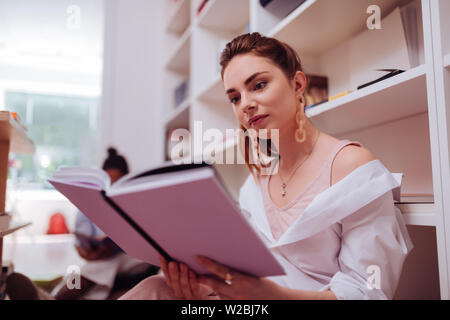 Liebe dieses Hotel. Bezauberndes Mädchen zum Ausdruck Positivität und lehnte sich auf Bücherregal Stockfoto