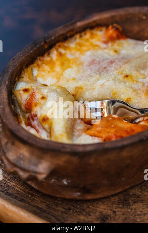 Die nationalen Montenegrinischen essen. Salziger Pfannkuchen mit Fleisch, saure Sahne und Käse in einem gusseisernen Topf auf einen Tisch im Restaurant. Stockfoto