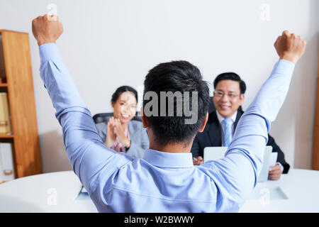 Glücklich, aufgeregt, jungen Mann, der vor der Personalleiter und Anheben der Arme Glück nach dem neuen Job Express Stockfoto