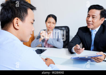 Reifen Vietnamesischen hr manager auf cv und fragen junge Antragsteller bei Treffen in großen Unternehmen Stockfoto