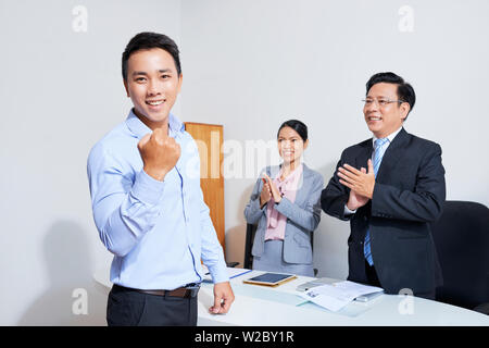 Glückliche junge vietnamesische Geschäftsmann machen Faustpumpe nach neuen Job nach Interview mit Human Resources Manager Stockfoto