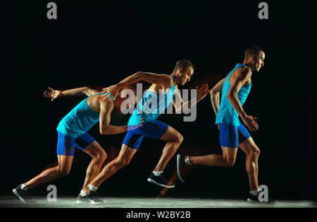 Professionelle männlichen Läufer Training auf Schwarz studio Hintergrund in gemischten Licht isoliert. Mann in sportsuit üben in Laufen oder Joggen. Gesunder Lebensstil, Sport, Gymnastik, Bewegung und Action Concept. Stockfoto