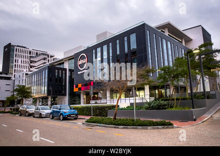 Kapstadt, Südafrika, 12. April 2019: Moderne Büro Gebäude mit Glasfassade von gepflegten Bäumen umgeben ist. Stockfoto