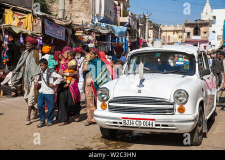 Indien, Rajasthan, Pushkar, Leute, die einen weißen Botschafter Auto auf dem Weg nach Pushkar camel Fair Stockfoto