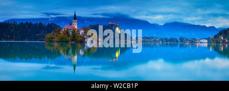 Die Insel (Blejski otok) mit der Kirche Mariä Himmelfahrt (Cerkev Marijinega vnebovzetja) & Burg von Bled leuchtet in der Dämmerung, der See von Bled, Bled, Obere Krain, Julische Alpen, Slowenien Stockfoto