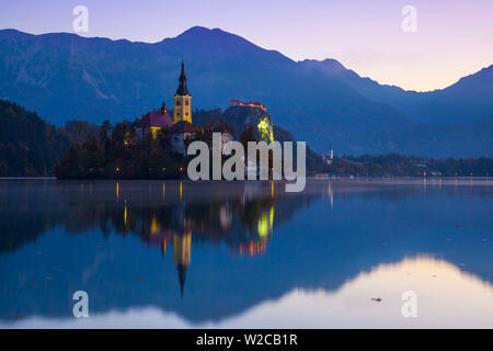 Die Insel (Blejski otok) mit der Kirche Mariä Himmelfahrt (Cerkev Marijinega vnebovzetja) leuchtet in der Dämmerung, der See von Bled, Bled, Obere Krain, Julische Alpen, Slowenien Stockfoto