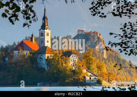 Die Insel (Blejski otok) mit der Kirche Mariä Himmelfahrt (Cerkev Marijinega vnebovzetja) & Burg von Bled beleuchtet bei Sonnenaufgang, der See von Bled, Bled, Obere Krain, Julische Alpen, Slowenien Stockfoto