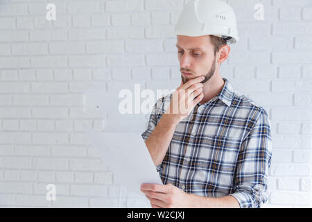Nachdenklich Ingenieur in harten Hut Lesen eines Dokuments Stockfoto