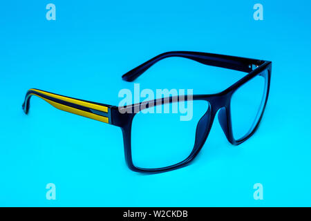 Computer Augenschutz Brille mit einem gelben Bügel in der Nähe auf einem blauen Hintergrund, Isolation. Stockfoto