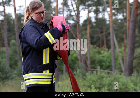 Alt Jabel, Deutschland. 08 Juli, 2019. Ein Feuerwehrmann wickelt Schläuche am Rande der Munition kontaminierten Bereich auf dem ehemaligen Truppenübungsplatz. Eine Woche nach dem Ausbruch der verheerenden Waldbrand in der Nähe von Lübtheen im südwestlichen Mecklenburg, die Flammen in der Gegend, die stark mit Munition verunreinigt, haben gelöscht, nach dem Befehl. Auf einer Fläche von etwa 500 Hektar, es gibt noch glühende Nester im Boden, sind genau zu beachten. Insgesamt 1.200 Hektar Wald waren betroffen. Credit: Jens Büttner/dpa-Zentralbild/dpa/Alamy leben Nachrichten Stockfoto