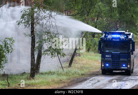 Alt Jabel, Deutschland. 08 Juli, 2019. Die Polizei Wasserwerfer löscht einzelne leuchtende Nester im Wald auf dem ehemaligen Truppenübungsplatz. Eine Woche nach dem Ausbruch der verheerenden Waldbrand in der Nähe von Lübtheen im südwestlichen Mecklenburg, die Flammen in der Gegend, die stark mit Munition verunreinigt, haben gelöscht, nach dem Befehl. Auf einer Fläche von etwa 500 Hektar, es gibt noch glühende Nester im Boden, sind genau zu beachten. Insgesamt 1.200 Hektar Wald waren betroffen. Credit: Jens Büttner/dpa-Zentralbild/dpa/Alamy leben Nachrichten Stockfoto