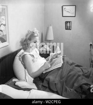 Frau der 40er Jahre. Eine junge Frau liegt im Bett liest die Morgenzeitung und trinkt Kaffee. Schweden 1948. Kristoffersson ref EIN 61-3 Stockfoto