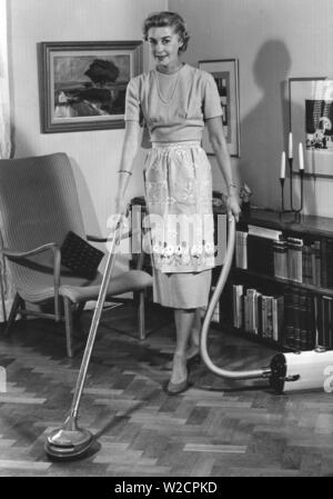Reinigung Tag in den 1950er Jahren. Eine junge hausfrau wird Staubsaugen den Boden mit dem neuesten Modell von Electrolux. Das Modell kann auch verwendet werden, um Böden zu polieren und verwendet sie das Gerät. Schweden 1950 Stockfoto