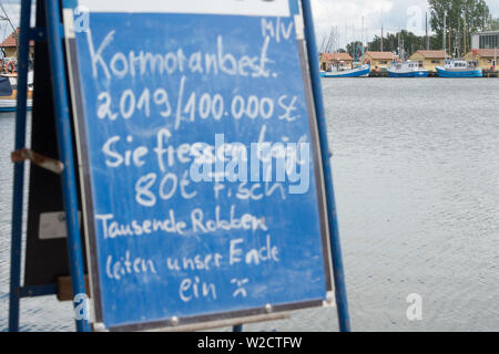 05 Juli 2019, Mecklenburg-Vorpommern, Freiesten: Im Hafen gibt es ein Schild mit dem Schlag' Kormoranbestand 2019/100000 Stück' in einer Fischerhütte eines Fischers der Fischereigenossenschaft Freiesten. Sie essen 80 t Fisch pro Tag - Tausende von Dichtungen sind unser Ende". Der Bundesminister für Ernährung und Landwirtschaft Klöckner mit Mecklenburg-Vorpommerns Landwirtschaftsminister Backhaus und Angeln Verbände am 8. Juli 2019 zu Gesprächen über Fangquoten 2020, sofortige Maßnahmen auf Dorsch in der Ostsee und die Fangmengen in der Sportfischerei. In Sassnitz-Mukran auf der Insel Rügen, der Minister visi Stockfoto