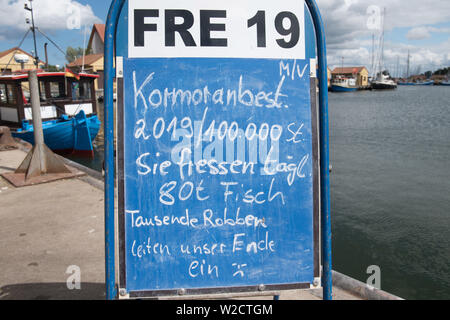 05 Juli 2019, Mecklenburg-Vorpommern, Freiesten: Im Hafen gibt es ein Schild mit dem Schlag' Kormoranbestand 2019/100000 Stück' in einer Fischerhütte eines Fischers der Fischereigenossenschaft Freiesten. Sie essen 80 t Fisch pro Tag - Tausende von Dichtungen sind unser Ende". Der Bundesminister für Ernährung und Landwirtschaft Klöckner mit Mecklenburg-Vorpommerns Landwirtschaftsminister Backhaus und Angeln Verbände am 8. Juli 2019 zu Gesprächen über Fangquoten 2020, sofortige Maßnahmen auf Dorsch in der Ostsee und die Fangmengen in der Sportfischerei. In Sassnitz-Mukran auf der Insel Rügen, der Minister visi Stockfoto